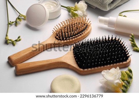 Wooden hairbrushes, different cosmetic products and beautiful flowers on white background Royalty-Free Stock Photo #2296136779
