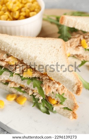 Delicious sandwiches with tuna, corn and greens on serving board, closeup