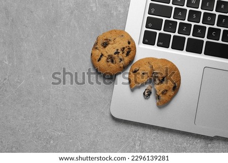 Chocolate chip cookies and laptop on light grey table, flat lay. Space for text