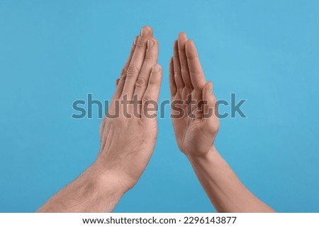 People giving high five on light blue background, closeup Royalty-Free Stock Photo #2296143877