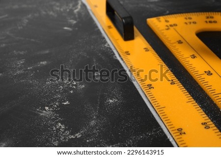 Ruler and protractor with measuring length and degrees markings on blackboard, closeup. Space for text