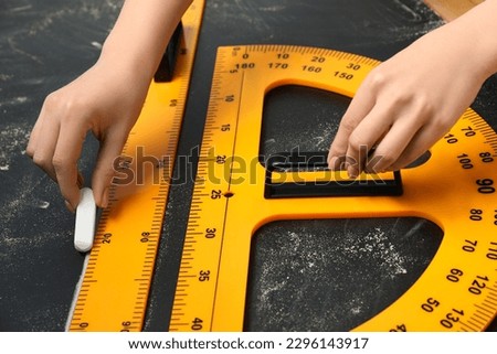 Woman drawing with chalk, ruler and protractor on blackboard, closeup