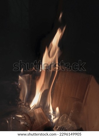 burning cardboard along with plastic waste that is burned over medium heat with a black background at night