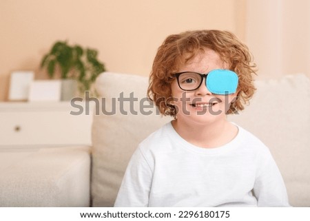 Happy boy with eye patch on glasses indoors, space for text. Strabismus treatment Royalty-Free Stock Photo #2296180175
