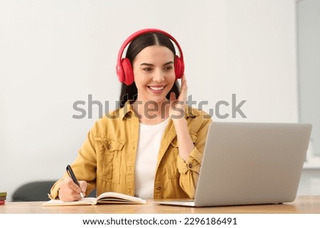 Online translation course. Student in headphones writing near laptop at home