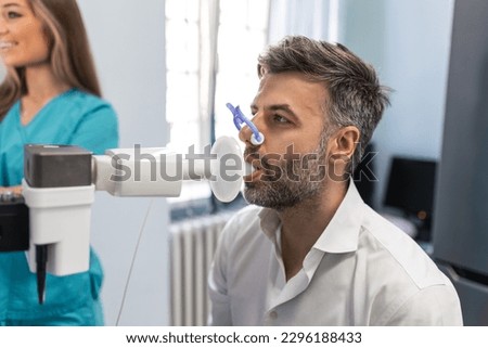 Man performing pulmonary function test and spirometry using spirometer at medical clinic. Spirometry of lungs Royalty-Free Stock Photo #2296188433