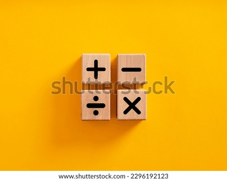 Basic mathematical operations symbols. Plus, minus, multiply and divide symbols on wooden cubes on yellow background. Mathematic or math education and basic calculations for business concept. Royalty-Free Stock Photo #2296192123