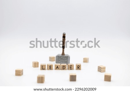 The hammer is standing on the wooden cubes with the word LEADER against white background