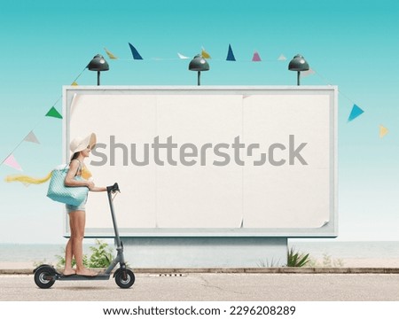 Young happy woman riding an e-scooter and going to the beach, large billboard in the background
