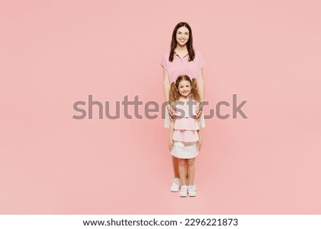 Full body smiling happy woman wear casual clothes with child kid girl 6-7 years old. Mother stand behind daughter, looking camera isolated on plain pastel pink background. Family parent day concept Royalty-Free Stock Photo #2296221873