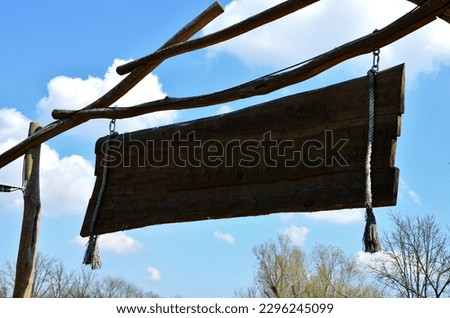 wesrltern style billboard sign. the board at the top of the gate hangs on ropes. ranch entry to yard. Apache museum in nature. tassels