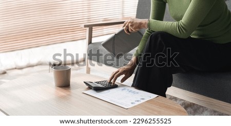 Young woman using calculator for paperwork, counting expenses, spending, analyzing tax, receipts, calculating budget. Economy, finance concept