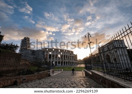 Rome, path to the Colosseum from Titus Arch at sunrise, with passing cyclist