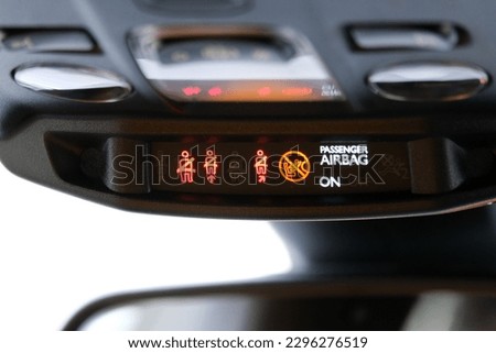 Seat belt and passenger airbag light showing on the car rear view mirror inside the car under the headlight. Signs inside the car. Selective focus. 
 Royalty-Free Stock Photo #2296276519