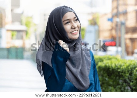 Happy smiling successful young muslim woman looking up, outdoor urban background