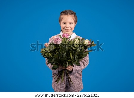 Smiling european little girl with bouquet of flowers enjoy spring birthday isolated on blue background, studio. Greeting, holiday celebration, congratulation, childhood and emotions