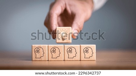 brainstorming creative idea and innovation. Hand putting over wooden cube block with light bulb icon on many people together having an idea symbolized by icons on cubes. Royalty-Free Stock Photo #2296342737