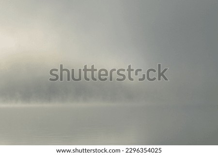 Dense fog at dawn on the lake