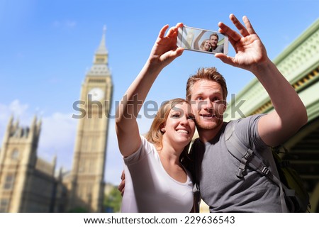 happy couple selfie by smart phone in london with big ben background, caucasian