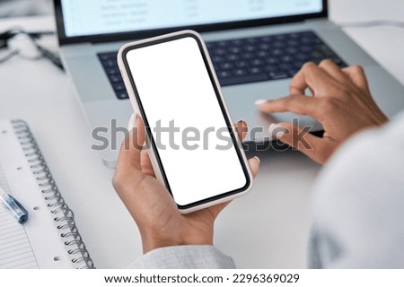 Smartphone electronic gadget blank white screen mockup in hand sitting at workplace in office. Digital communication, social media applications ads, shopping, delivery app, over shoulder close up. Royalty-Free Stock Photo #2296369029