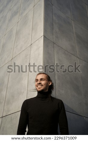 Urban simplicity and minimalism contemporary. Portrait of joyful smiling man against gray wall with symmetrical lines outside