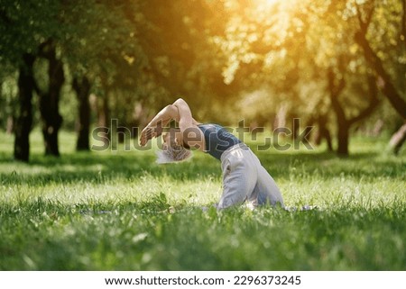 Young woman doing yoga exercise outdoor in the park, sport yoga concept                               