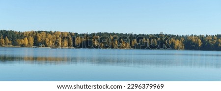 Gold, green autumn landscape in the Russian countryside. Water in the lake is calm. Sun is everywhere in the october. Clear sky. Fresh cold air. Concept of the beauty in nature. Panoramic photography