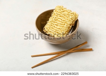 Raw instant noodles in bowl with chopsticks on white grunge background Royalty-Free Stock Photo #2296383025