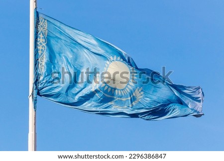 Flag of the Republic of Kazakhstan waving in the wind against the blue sky.