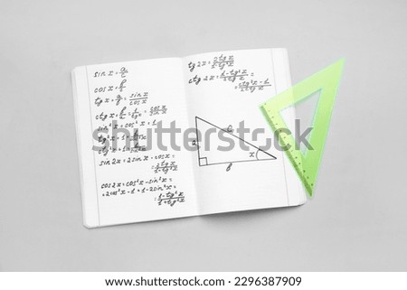 Copybook with maths formulas and ruler on grey background Royalty-Free Stock Photo #2296387909