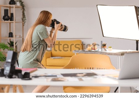 Young female photographer with professional camera taking picture of succulents in studio
