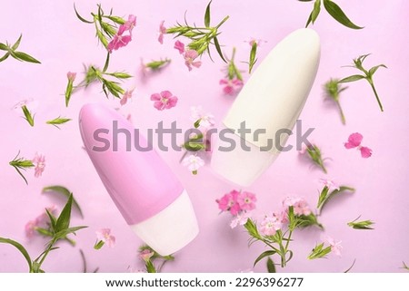 Deodorant bottles and flowers on pink background Royalty-Free Stock Photo #2296396277