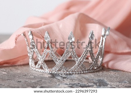 Beautiful crown with prom dress on grunge table, closeup
