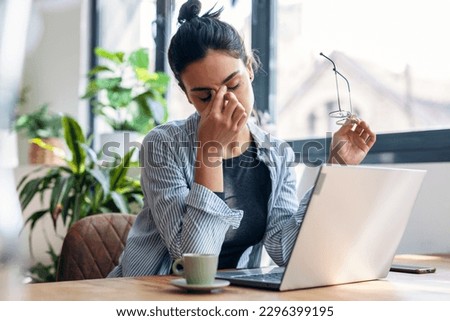 Shot of stressed business woman working from home on laptop looking worried, tired and overwhelmed