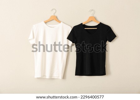 Black and white t-shirts hanging on grey wall