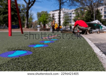 A mason hand with trowel  spreading and leveling soft rubber crumbs rubber mulch 
for children's playground. Outdoor soft coating and floor covering for sports. Rubber surface for safety. Royalty-Free Stock Photo #2296421405