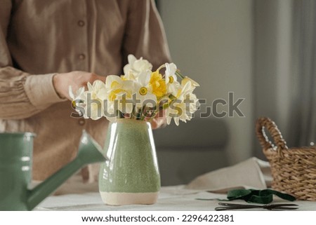 Woman puts a bouquet of fresh flowers into a vase. Decoration and creation of comfort in the house concept
