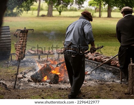 gaucho cooking the meat on the fire, making the barbecue on the coals Royalty-Free Stock Photo #2296422977