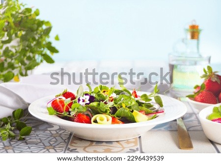 Spring healthy fresh salad with green, edible flowers pansies viola and strawberries.