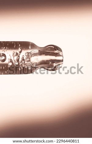 Dropper with hyaluronic acid close-up on a beige background. Beauty background with pipette and care product.