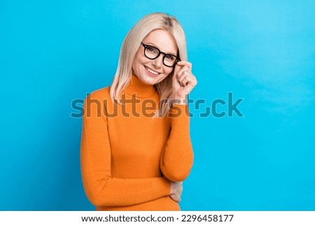 Photo of satisfied cute blonde hairstyle good mood lady wear orange turtleneck touch eyeglasses smiling isolated on cyan color background
