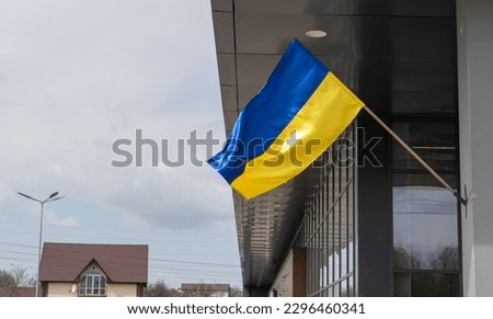 The national flag of Ukraine flutters in the wind on a flagpole, on a building. Blue and yellow colors on the Ukrainian flag. Flag of Ukraine on the facade of the government building
