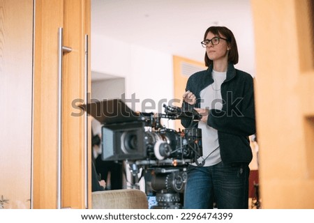 The director is a woman at work on the set. The director works with a group or with a playback while filming a movie, advertising, or a TV series. Shooting shift, equipment and group.  Royalty-Free Stock Photo #2296474399