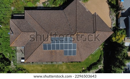 The image shows an aerial shot of a modern house with a solar panel system installed on its roof.