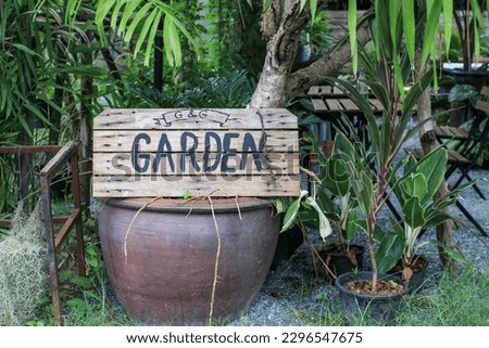 Garden sign on wooden located in a public park. The sign directs visitors around the various types of plants and flowers growing.