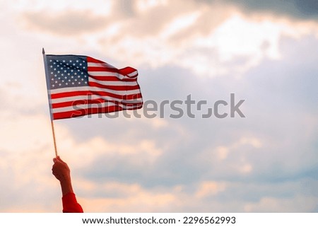 
Hand Waving the Flag of the United Stated of America. Optimistic person holding American flag celebrating citizenship
 Royalty-Free Stock Photo #2296562993