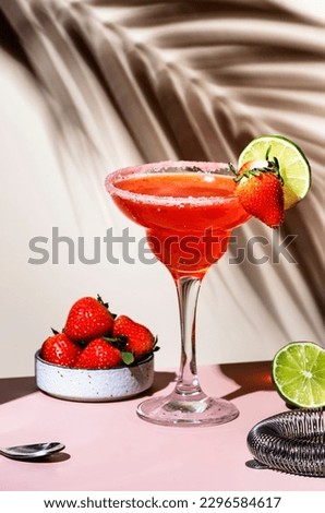 Strawberry Margarita summer cocktail drink with silver tequila, lime juice, liqueur, fresh berries and ice in glass with salt rim. Beige pink background., hard light, shadow pattern Royalty-Free Stock Photo #2296584617