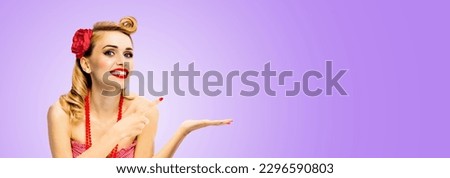 Wide photo of happy excited smile woman hold, give, promote, pointing ad. Blond girl in pin up style, show copy space for text. Retro fashion and vintage. Isolated light purple violet background
