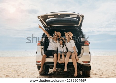 Happy Family Day. Family travel in holiday at sea beach, Dad, mom, daughter enjoy road trip sitting on back car and pointing finger out, people having fun in summer vacation on beach with automobile Royalty-Free Stock Photo #2296604469
