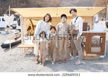A family lined up in front of a tent at a campsite